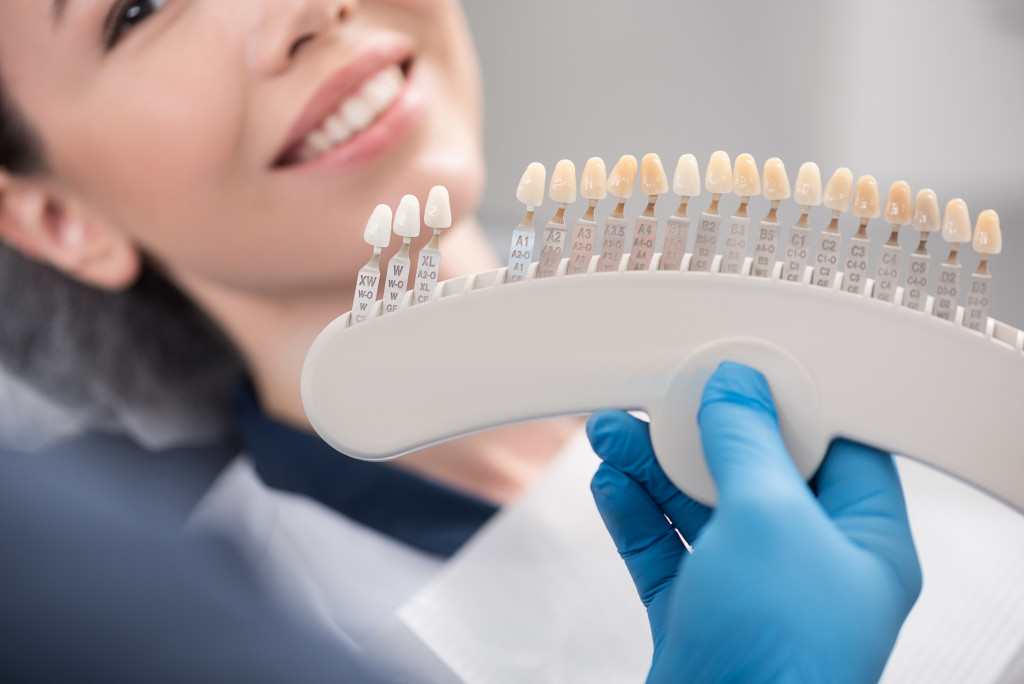 a woman smiling while dentist compares model teeth 
