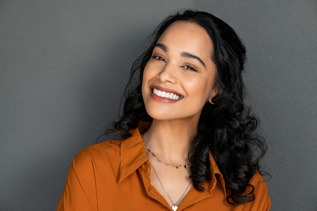 woman looking at camera against gray wall with a big whitening teeth smile