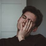 stressed man with his hand over his eye